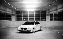 Белый тонированный BMW 7 series на автостоянке